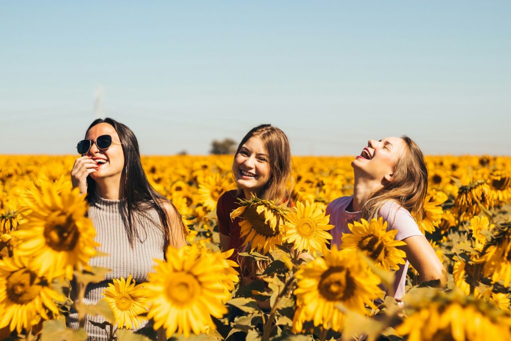 Mujeres sonriendo dentro de una plantación de girasoles disfrutando la vida sin estrés. El estrés se puede superar con la guía y herramientas adecuadas de un psicólogo experto.